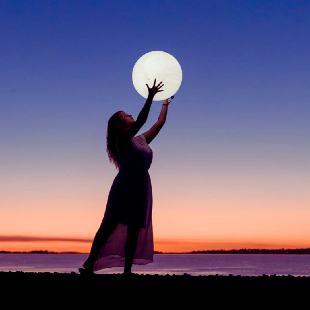 Moon Gazing Woman holding up a Full Moon ball in the night sky