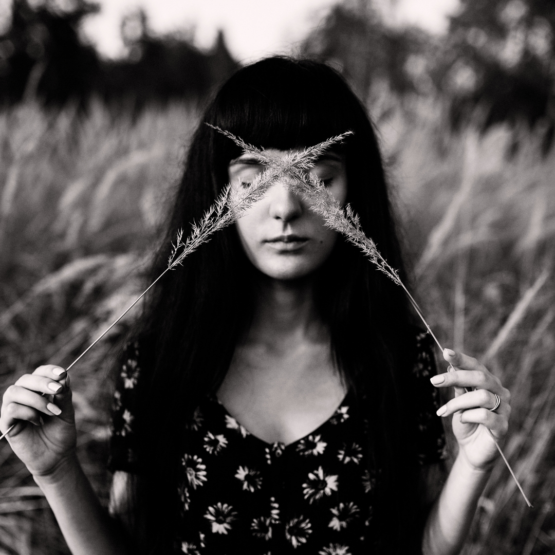 Woman with long dark hair in corn field embodying her feminine energy