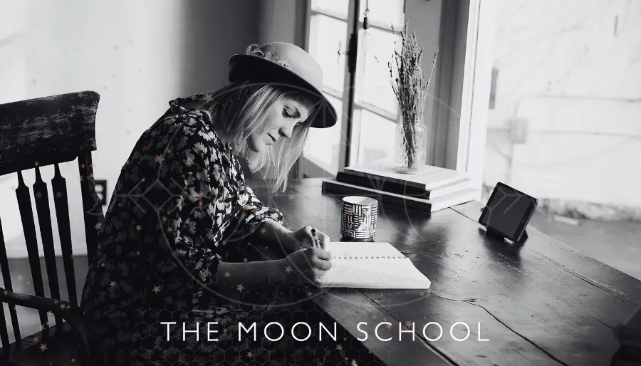 Woman with hat sitting at wooden table writing