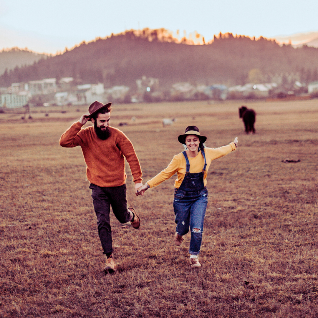 Boho couple running through field happy