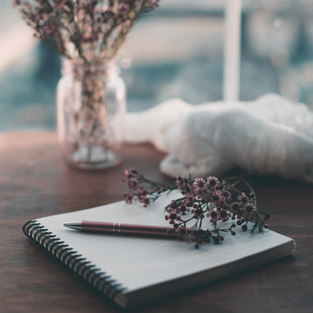 journal with pen and flowers for writing in response to shadow work journal prompts