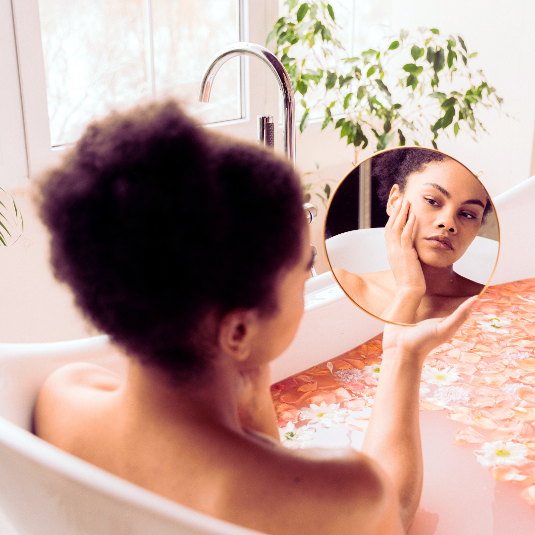 Woman of colour in a moon bath looking at her reflection in a mirror
