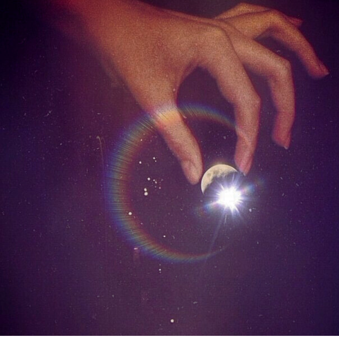 Hand reaching into sky to hold waxing crescent Moon spiritual