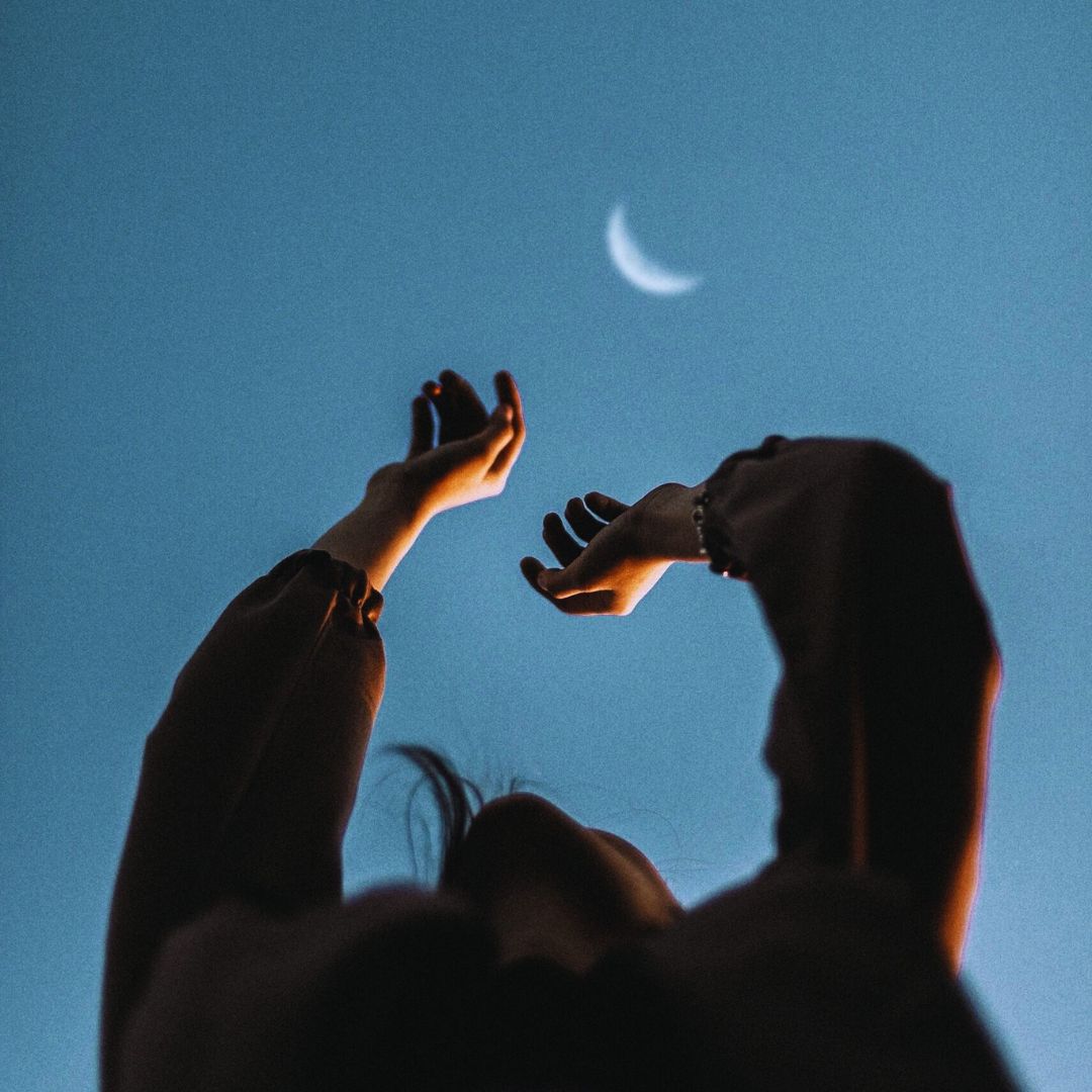 hands reaching up towards waning crescent Moon