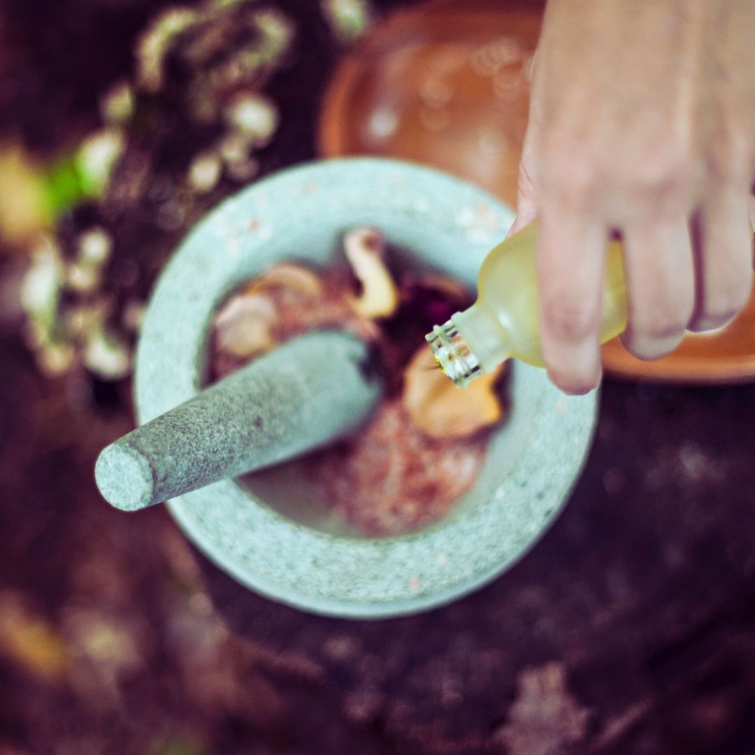 Hand pouring essential oil into mortar and pestle for new Moon ritual