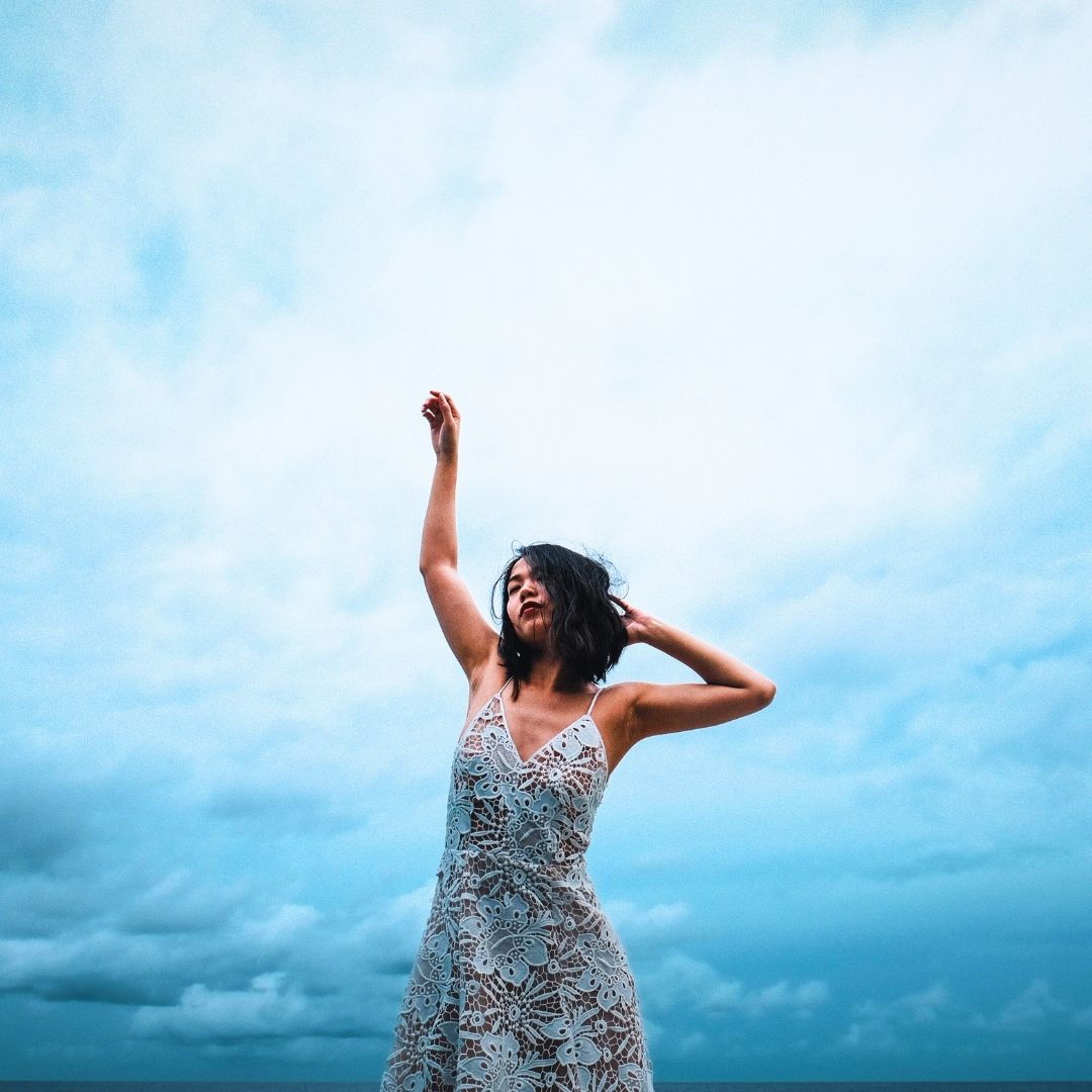 woman reaching up to blue sky opening up to the energy of the Moon