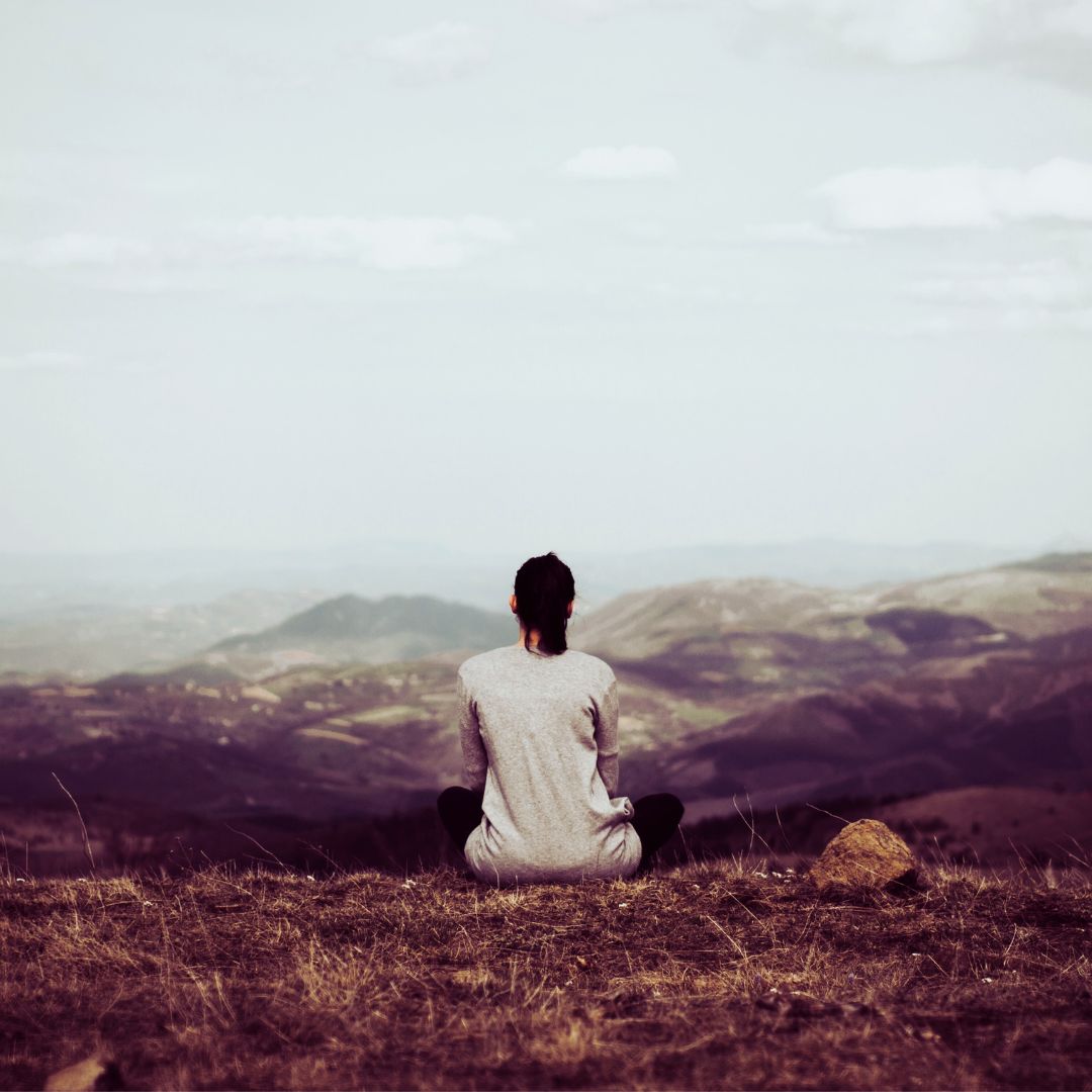 Woman sitting on a hilltop doing a cord cutting ritual 