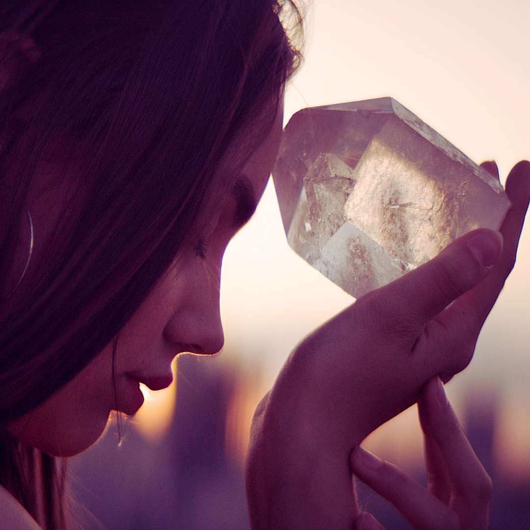 spiritual woman holding crystal up to third eye