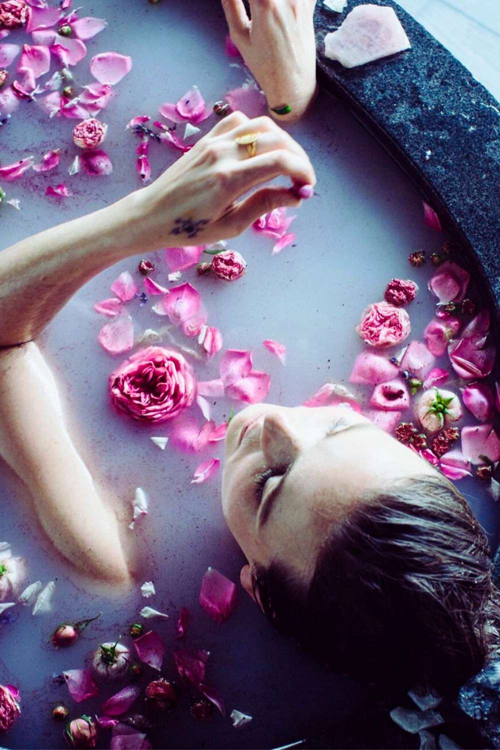 Woman relaxing in a healing rose petal bath ritual