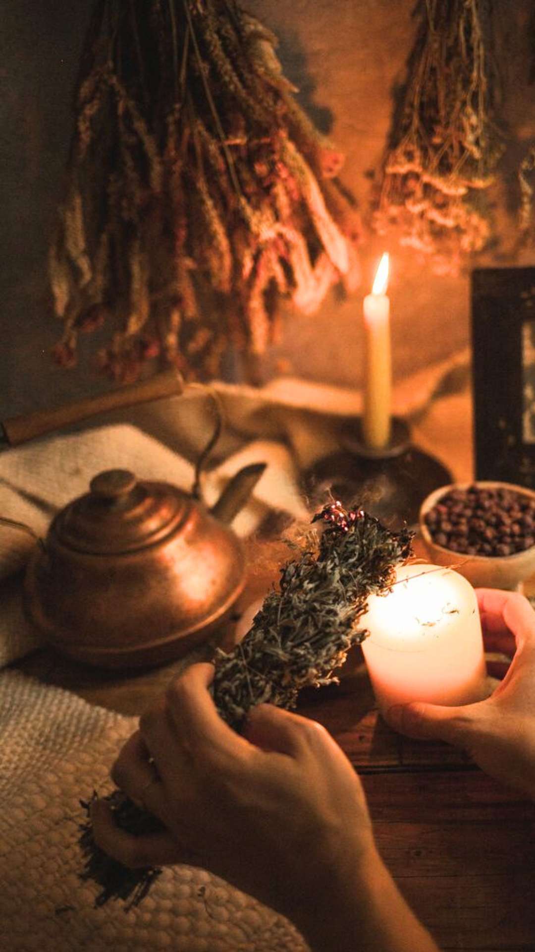 Wiccan women lighting a herbal bundle to create sacred space at samhain
