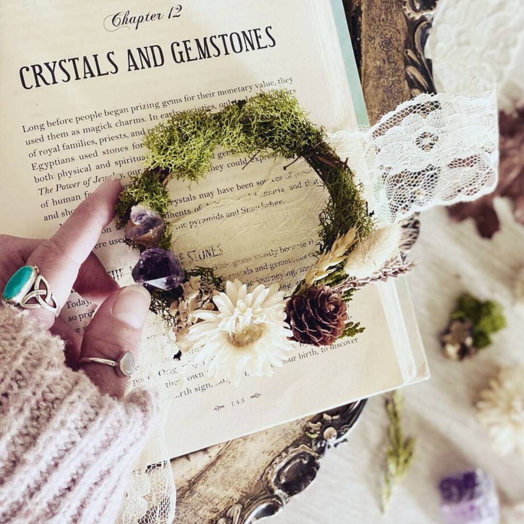 Mini woodland-inspired wreath placed on book open onto a page titled: crystals and gemstones 