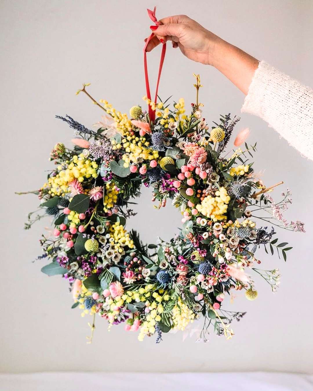Stunning photo of a spring wreath in pastel colours held by red ribbon