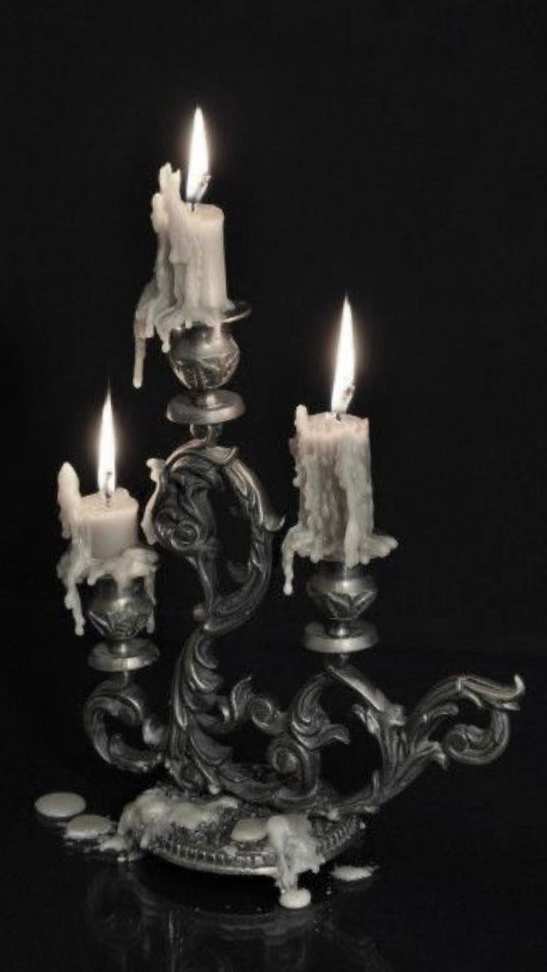 Black and white image of White candles in a witchy gothic style holder